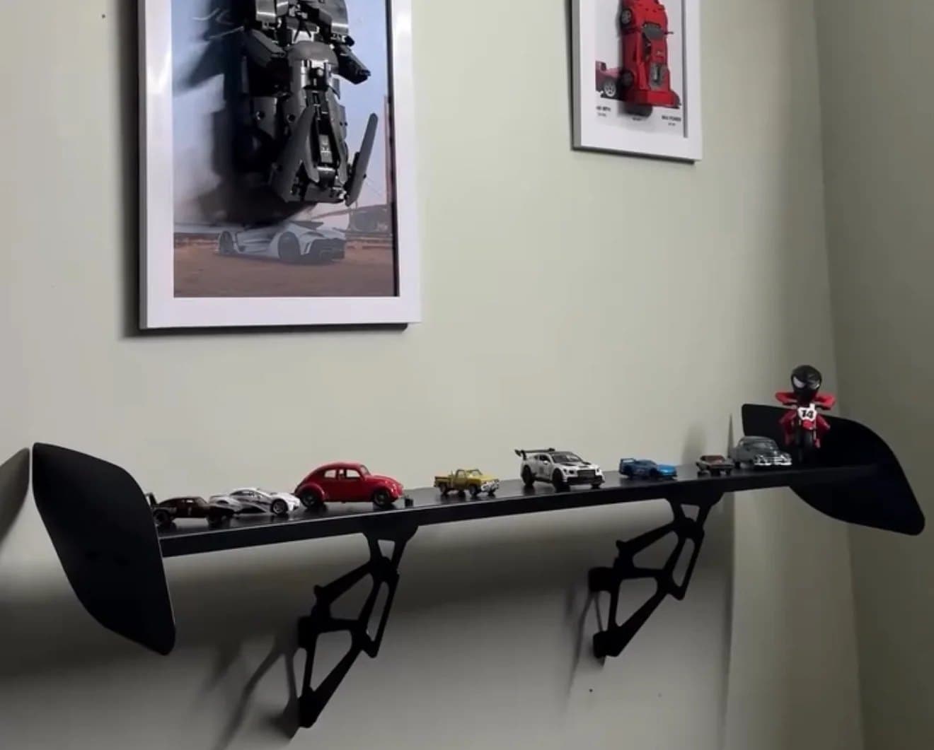 Le Spoiler Shelf fixé au mur, sa lame garnie de voitures miniatures, porté par deux jambes squelettes